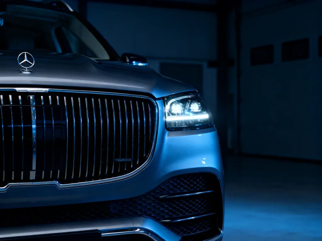 Zbliżenie na nowoczesny grill i reflektory BMW X5 G05 w minimalistycznym, garażowym otoczeniu.